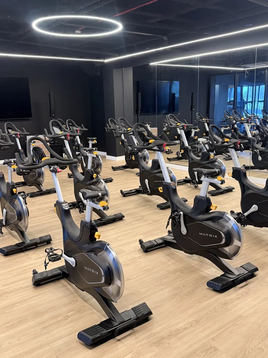 Sala de spinning com bikes e iluminação circular